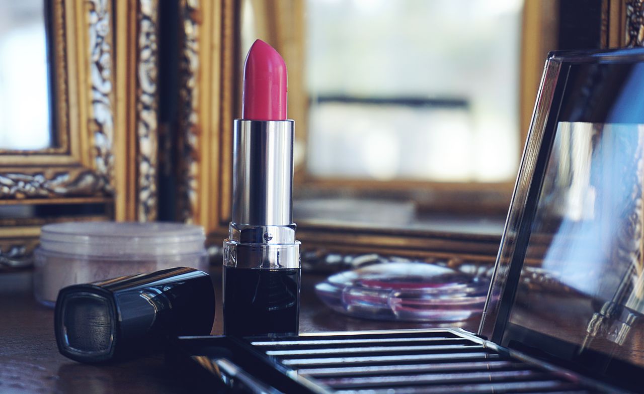 who-we-are Elegant close-up of pink lipstick on a stylish makeup vanity with reflections.