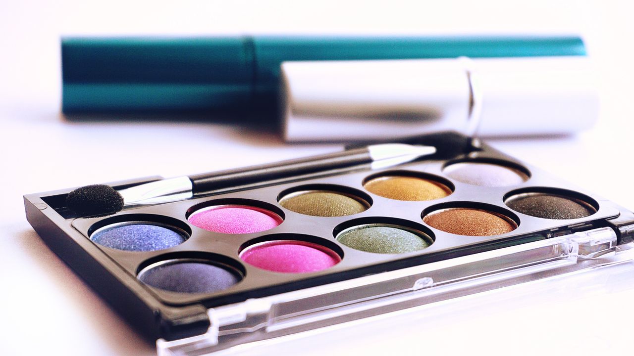 services-01 Close-up of colorful eyeshadow palette with brush, ideal for fashion and beauty themes.
