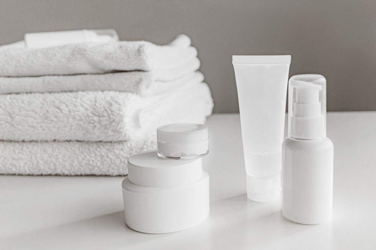 services-04 Minimalist arrangement of white skincare products and towels for a modern aesthetic.